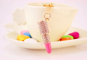 Macro view of a gold-tone lipstick keychain with pink stones and sparkling rhinestones