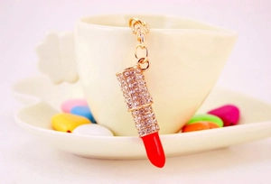 Detailed view of rhinestone lipstick keychain hanging on a white ceramic cup handle