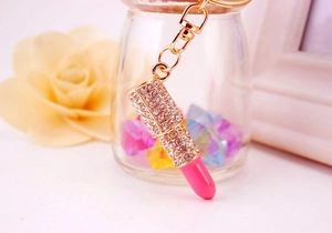 Macro shot of a gold metal lipstick keychain with pink rhinestones for women's bags