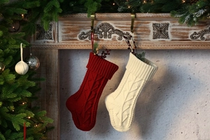 Close-up of knitted Christmas stockings with cable pattern hanging on a festive fireplace