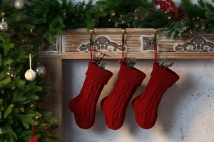 Close-up of three red cable-knit Christmas stockings with hanging loops for holiday decor