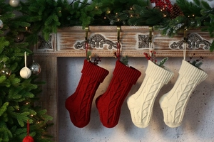 Close-up of red and beige knitted Christmas stockings hanging on a festive wooden mantel