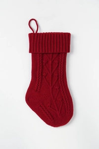 Detailed view of a red knitted Christmas stocking with cable knit patterns and leaves