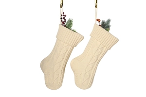 Detail of cream cable knit Christmas stockings with red berries and pine needles