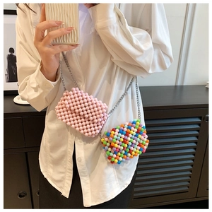 Mini candy colored beaded crossbody bags with metal chains shown on a model