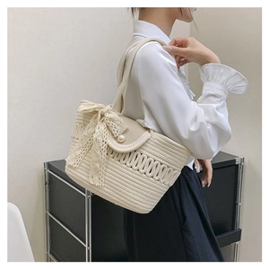 Detail of cream woven handbag featuring a delicate lace bow and pearl buckle accent