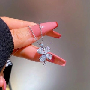 Macro shot of silver titanium clover pendant featuring shimmering inlaid crystals on a chain