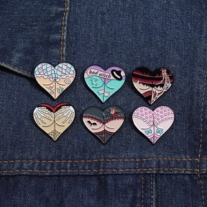 Close-up of six creative heart-shaped enamel pins on denim, featuring bad witch and skull hand