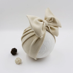 Detailed close-up of beige faux cashmere baby turban hat with a large decorative bow