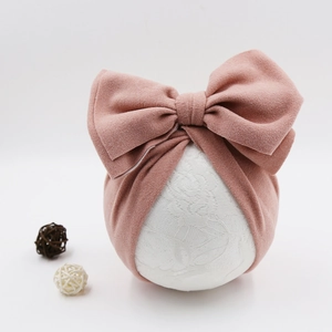 Close-up of soft pink baby turban headband with large bow detail on a white model