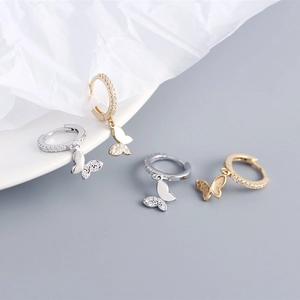 Close-up of butterfly hoop earrings in silver and gold with diamond accents