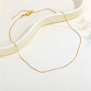Elegant gold box chain necklace with lobster clasp displayed on a minimalist white tray