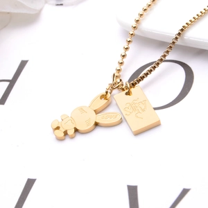 Close-up of 18K gold rabbit and rectangular pendant with LOVE engraving on a ball chain