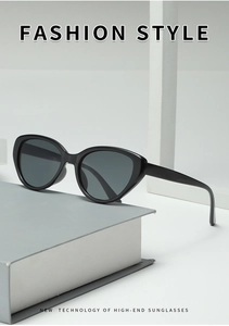 Close-up of vintage black oval cat-eye sunglasses with dark lenses on a grey book