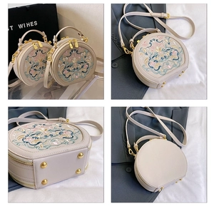 Detail view of beige round crossbody bag featuring Chinese embroidery and gold hardware
