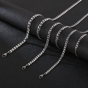 Men's silver stainless steel Cuban link necklace set on textured black background
