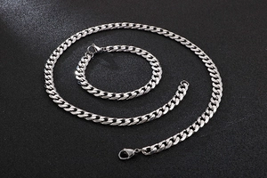 Detailed set of silver stainless steel Cuban link necklace and bracelet on dark background