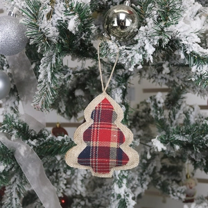 Linen Christmas tree ornament with plaid details hanging on a flocked holiday tree