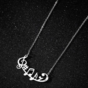 Macro shot of a silver musical note pendant featuring a G-clef on a black textured surface