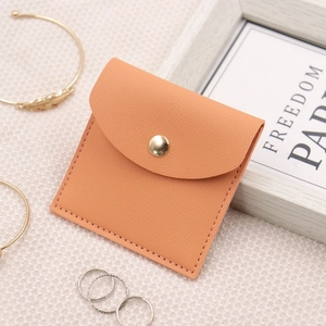 Macro shot of orange leather jewelry pouch featuring fine stitching and gold snap button