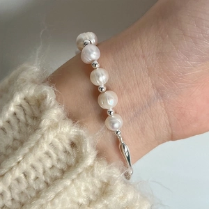 Baroque freshwater pearl bracelet with silver branch bangle worn on a white sweater