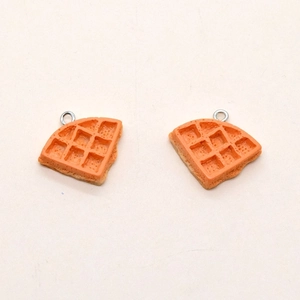 Macro detail of resin waffle charms with realistic texture and metal hanging loops