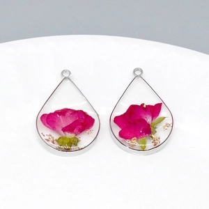 Close-up of teardrop resin pendant with red dried rose buds and gold foil flakes