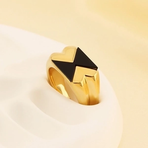 Dettaglio dell'anello in titanio dorato con motivi geometrici in smalto nero a cuore