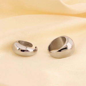 Close-up of polished silver steel chunky open rings on textured fabric background