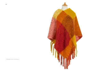 Detail of warm-toned chunky tassel and soft plaid knit texture on autumn poncho