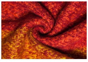 Macro detail of red and yellow gradient knit shawl with thick textured wool blend yarns