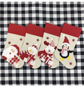 Flat lay of four large burlap Christmas stockings with Santa, snowman, and reindeer motifs