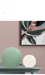 Leaf-shaped ceramic vases in light green and cream with detailed vein textures on grey table