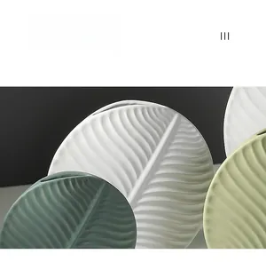 Detail of leaf-shaped ceramic vase showing textured leaf veins in matte green and white