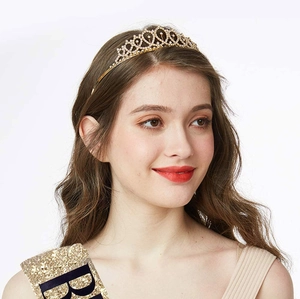 Detail of glittering gold birthday crown with rhinestones and matching party sash on model