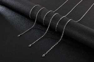 Detail of silver twisted rope chains in various lengths on black textured fabric