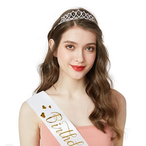 Close-up of sparkling rhinestone crown and gold lettering birthday sash on a model