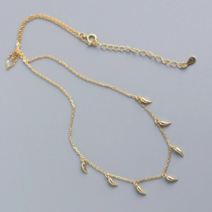 Detail einer Goldhalskette mit mehreren kleinen hornförmigen Anhängern an einer O-Kette