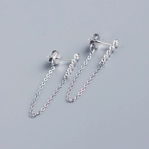 Detail of silver long drop earrings with a row of sparkling tassels on a grey background