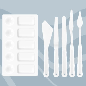 Flat lay of a white 10-well plastic palette with five assorted palette knives for painting