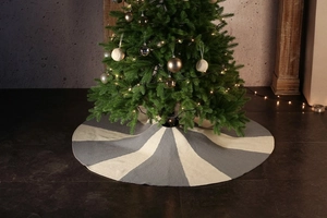 Close-up of knitted Christmas tree skirt in grey and white stripes with festive lighting