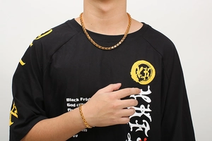 Close-up of golden stainless steel necklace and bracelet set worn by a model on white background