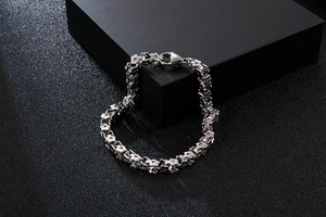 Detail of silver stainless steel flower link bracelet with lobster clasp on black background