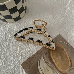 Detail of checkered hair claw clip on textured background with artistic accessories