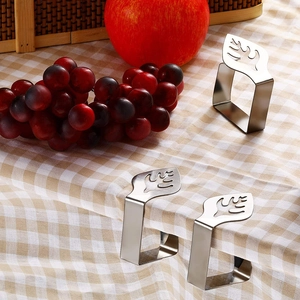 Detail of three stainless steel leaf-shaped tablecloth clips on a plaid tablecloth