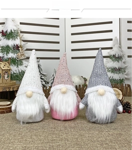 Detailed view of three knitted Christmas gnomes in white, pink, and grey with plush beards