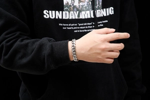 Close-up of men's chunky silver titanium steel cuban chain bracelet on a male wrist