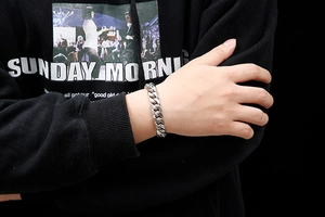 Close-up of a heavy silver stainless steel curb chain bracelet worn on a male wrist