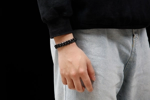 Close-up of black titanium steel Cuban link bracelet worn on male wrist over denim