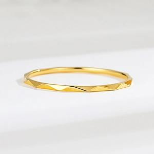 Detailed close-up of a minimalist faceted gold titanium ring on a geometric stand